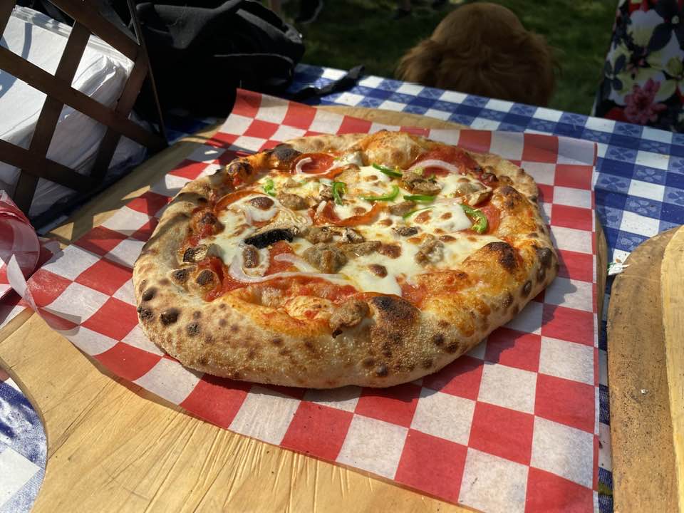Wood-fired pizza with fresh toppings on checkered paper